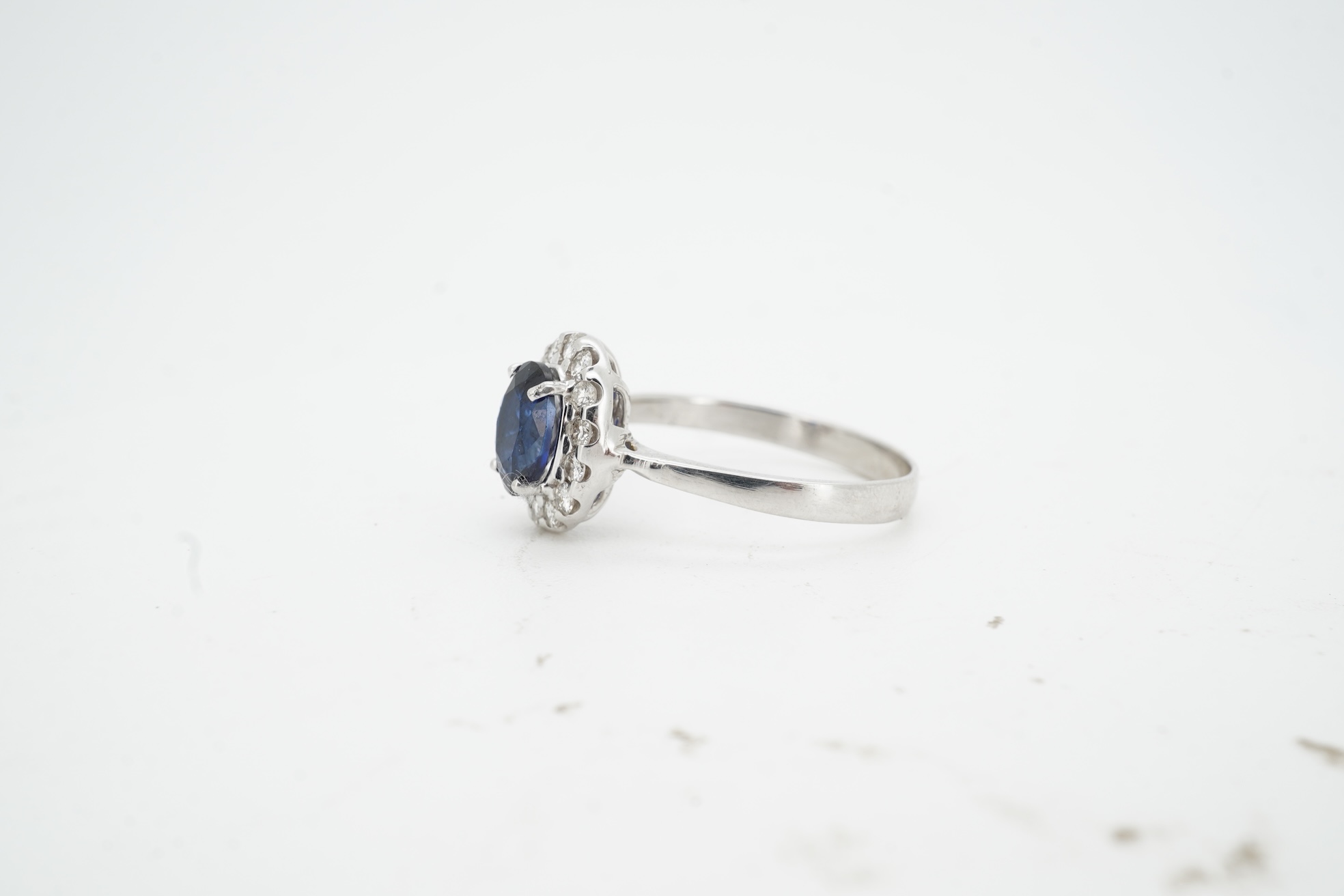 A synthetic sapphire and diamond cluster ring, mounted in white gold, size L1/2, stamped 18K, gross weight approximately 1.5 grams